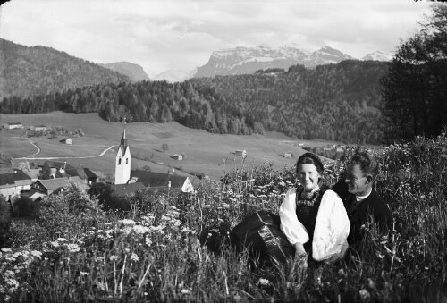 Ein Paar in Tracht mit Schwarzenberg und Kanisfluh im Hintergrund