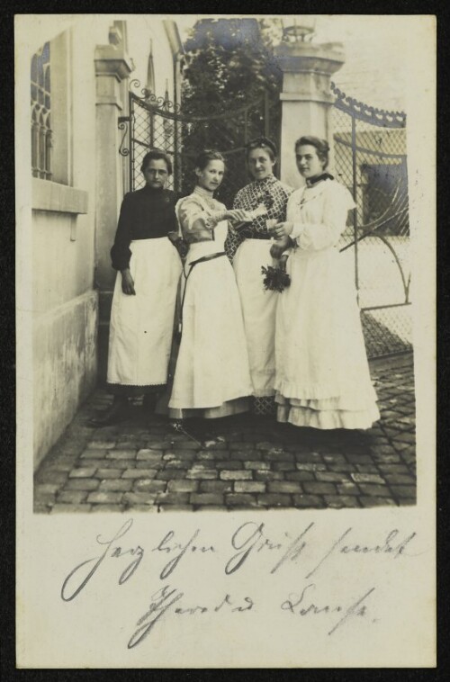 Vier unbekannte Frauen vor einem schmiedeeisernen Tor