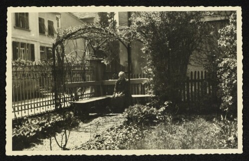 Ältere Frau auf einer Gartenbank unter einer Pergola in der Bregenzer Oberstadt