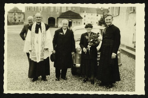 Gruppenaufnahme anlässlich einer Feier, vermutlich einer Goldenen Hochzeit, mit zwei Priestern vor einem Auto vor der Bregenzer Maria-Hilf-Kirche
