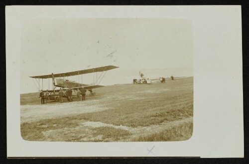 Doppeldecker-Flugzeug auf einem Flugfeld mit Personengruppe