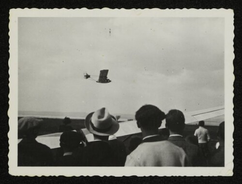 Segelflugzeug im Flug und Zuschauer im Vordergrund
