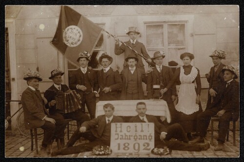 Gruppenaufnahme von Stellungspflichtigen des Jahrgangs 1892 mit Harmonikaspieler und Fahne